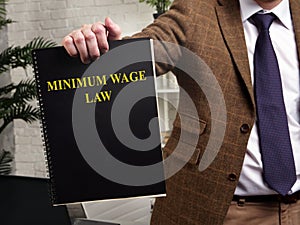 Man in a suit shows a book minimum wage law.