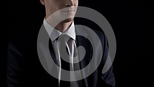Man in suit smirking,  on black background, unfair business concept