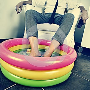 Man in suit soaking his feet in an inflatable water pool, with a photo