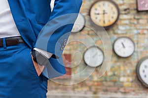 Man in suit standing near wall with clocks