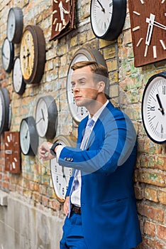 Man in suit standing near wall with clocks