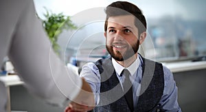 Man in suit and tie give hand as hello in office