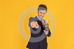 A man in a suit with a tie Handsome looking face with beard In the business man look Holding a trophy and pointing at you In the