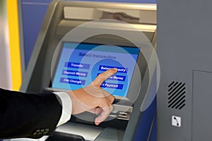 Man in suit touching display screen at ATM terminal