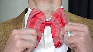 A man in a suit is trying on a funny red bow or bow tie. Funny men`s fashion