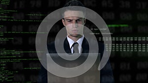 Man in suit typing on laptop, software code on background, password hack