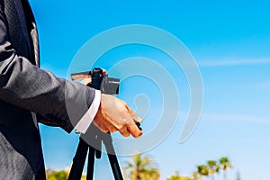 Man in a suit using a compact photo camera on a tripod to take a self-portrait to use as a profile in his business and social