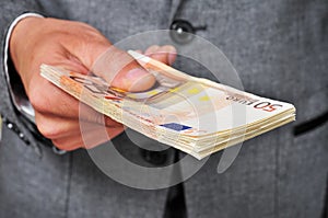 Man in suit with a wad of euro bills