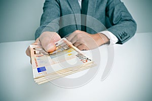 Man in suit with a wad of euro bills photo