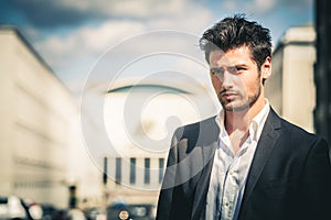 Man in suit and white shirt looking. Outdoors on the street in the city