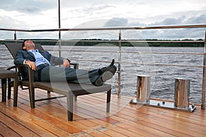 Man in suit, who rests in chaise lounge on wharf