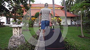 Man with suitcase settles in a hotel.