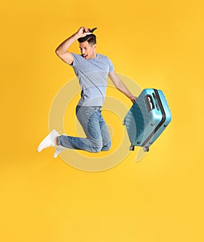 Man with suitcase for summer trip jumping on yellow background. Vacation travel