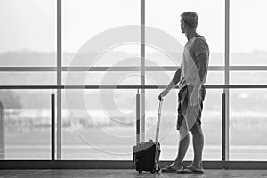 Man with suitcase waiting a plane at terminal airport