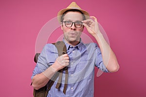 Man in sumer hat adjusting glasses looking interested with news