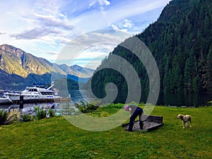 A man on summer boating trip, walking his dog and playing horseshoes, in the beautiful remote location of Indian Arm