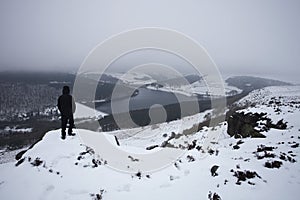 Man on summit looking towards snow covered valley