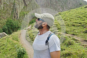 Man in sun glasses and hat somewhere in mountains. Person with a backpack. Travelling background. Adventure time.