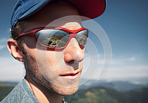 Man in sun glasses with mountain mirorred in it