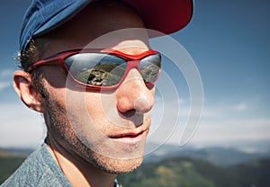Man in sun glasses with mountain mirorred in it photo
