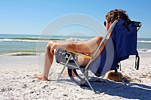 Man Sunbathing on Beach by Ocean