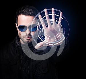 Man in sunglasses controls virtual system by hand.