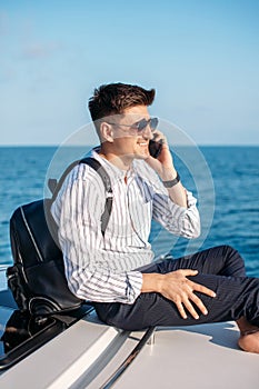 Man in sunglasses driving a yacht and talking on the phone