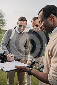 Man in sunglasses signing document on golf course