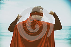 Man in superhero costume standing at sea shore