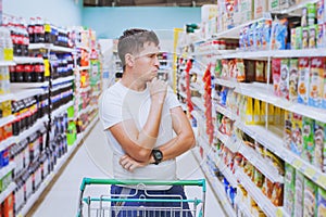 Man in the supermarket, customer thinking, choose what to buy