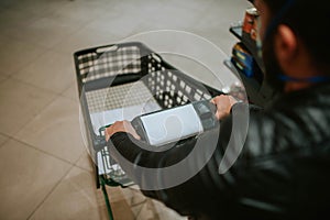 A man in a supermarket pushes a cart between the shelves