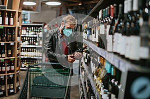 A man in a supermarket pushes a cart between the shelves