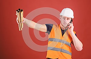 Man supervises construction on phone, red background. Engineer, architect on busy face speaks on phone, holds blueprints