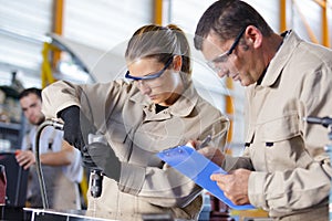 man supervising woman using bench drill