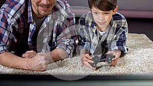 Man supporting his little son playing video game at home, family relationship