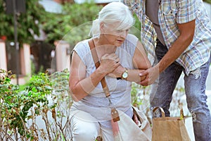 Man is supporting a woman feeling unwell on the street