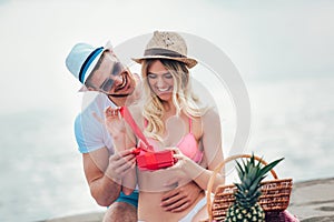 Man suprising his girlfriend with gift on the beach