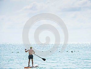 Man on surf boards in sea and Sunlight reflects the surface of the water at Koh Samet Pier , Rayong in Thailand. January 26, 2020