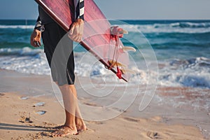 Man with a surfboard in his hands against the background of the ocean beach, active lifestyle