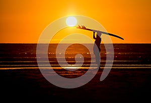 Man with surfboard in sunset at beach