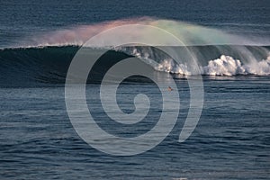 Perfect barrel wave with rainbow spray and surfer