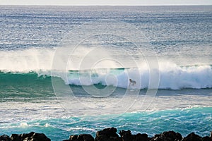 A Man Surfing on the Huge Waves in Pacific Ocean at Hanga Roa Town, Easter Island, Chile