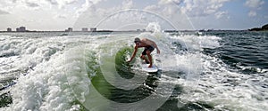 Man surfing skims the water with hand over a green wave