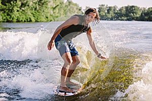 A man is surfing on a surfboard drawn by a motor boat above the wave of the boat. Weixerfer is engaged in surfing, entertainment,