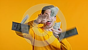 Man with surprised happy face scatters, waste money. Person overspend US currency. Guy is flush with dollars on yellow