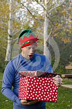 Man surprised by the two Christmas gifts he is holding.