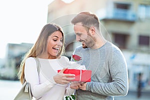 Man surprises woman with a gift and rose