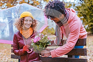 Man surprising his wife with a bouquet of flowers on a drizzly fall day