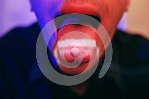 A man swallows a pill, a pill on his tongue, drugs, MDMA. photo