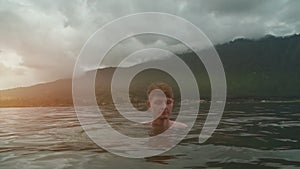 Man swim and meditate in lake by mountain of Bali